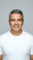 Confident middle-aged Hispanic man with gray hair smiling warmly in white t-shirt against neutral background for lifestyle and wellness content.