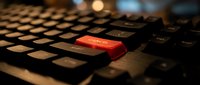 Red enter key on black computer keyboard with warm lighting creating dramatic tech atmosphere for cybersecurity and digital communication concepts.