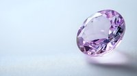 Pink oval cut gemstone on light background with soft shadow, luxury jewelry element for design. Precious stone with brilliant facets and sparkle.