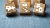 Healthcare wooden blocks with medical symbols ambulance stethoscope prescription on blue fabric background for medical insurance concepts.