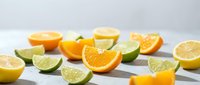 Fresh citrus fruit slices including orange, lemon and lime wedges arranged on white marble surface for healthy cooking and beverage preparation.