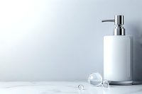White ceramic soap dispenser with chrome pump on marble surface, minimalist bathroom setting with crystal accents and soft light background.