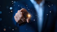 Professional in blue suit points at glowing magical light effect with sparkles and bokeh on dark background, demonstrating innovation and technology concept.