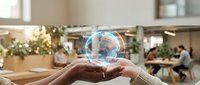 Hands holding holographic globe with digital network connections in modern office workspace representing global business technology and connectivity.