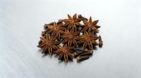 Aromatic star anise spices and cloves scattered on white background. Natural cooking ingredients for baking, tea blends and culinary recipes.