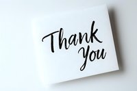 Modern brush lettering thank you message on white paper note card with soft shadow, minimalist gratitude greeting isolated on white background.