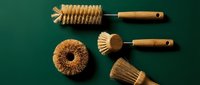 Eco-friendly wooden kitchen cleaning brushes set with natural bristles on green background for sustainable household cleaning and dishwashing tasks.