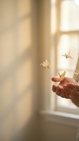 Hand holding golden paper cranes near sunlit window, symbolizing hope, wishes, and peaceful moments for wellness, mindfulness, and inspirational design projects.