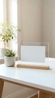 Minimalist acrylic photo frame with wooden base on white desk next to small succulent plant in modern bright interior for home office decor and branding.