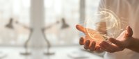 Businessman holding glowing light bulb in cupped hands representing innovation, creativity and bright ideas in modern office environment for business concepts.