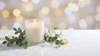 White candle with eucalyptus branches and pearls on marble surface against warm bokeh lights background for spa relaxation and home decor styling.