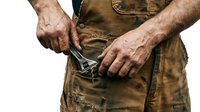Male worker in worn work apron checking empty wallet, depicting financial hardship, poverty, or economic struggle. Suitable for business, finance, labor, and social commentary projects.