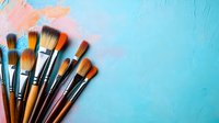 Paint brushes arranged in fan shape on textured background with pink and turquoise colors, artistic composition for creative projects and art supplies advertising.