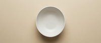 Empty white ceramic bowl on beige background, overhead view, isolated tableware for dining, kitchen, restaurant design, and food styling projects.