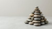 Balanced stone pyramid stack on neutral background symbolizing zen meditation mindfulness harmony wellness spa relaxation therapy balance stability.