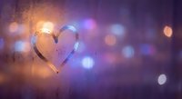 Heart drawn on foggy glass window with colorful bokeh lights creating romantic atmosphere for Valentine's Day celebrations and love concepts.
