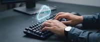 Businessman hands typing on keyboard with glowing cloud computing icon, digital transformation and data storage technology concept for modern office work.