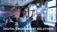 Young woman with long dark hair and light skin tone, wearing light blue shirt, interacting with holographic digital interface in modern office environment with colleagues working in background, representing technology innovation and business solutions.