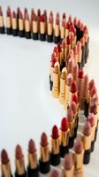 Curved line of luxury lipsticks in various nude and red shades with golden tubes arranged in artistic pattern on white background for beauty campaigns.