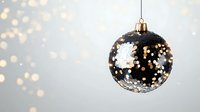 Black glossy Christmas ball with silver glitter pattern hanging against blurred bokeh lights background creating festive holiday atmosphere.