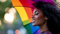 Joyful young African American woman with natural curly hair smiling against rainbow umbrella background with soft bokeh lights creating magical pride atmosphere.