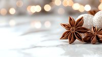 Star anise pods with glittering holiday decorations and soft bokeh lights create festive winter atmosphere on white marble background. Seasonal spice and decor.