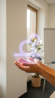 Hand holding glowing purple ampersand symbol with neon light effect in modern interior space with natural window light and potted plant background.