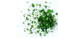 Fresh chopped parsley scattered on white background, overhead view of green herb leaves creating natural organic pattern for cooking and garnishing designs.