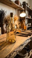 Rustic pottery workshop with amber glass bottle, dried herbs, ceramic vessels and warm lighting creating cozy artisan crafting atmosphere for handmade home decor.