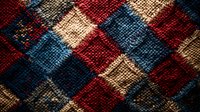 Vintage argyle knit pattern in red, navy blue and beige colors with textured wool fabric surface showing detailed close-up of diamond shapes and stitches.