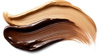 Smooth swirls of dark chocolate and beige foundation makeup smears isolated on white background, cosmetic texture swatches showing cream consistency.