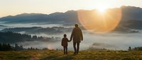 Adult and child hiking together at sunrise over misty mountain valley, enjoying outdoor adventure and nature exploration. Perfect for travel, family, and lifestyle content.