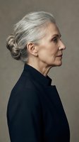 Senior woman with gray hair styled in a bun, wearing black shirt, shown in profile against neutral background. Mature female portrait for healthcare, wellness, and lifestyle content.