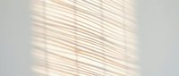 Soft diagonal shadow lines cast on white wall creating minimalist geometric pattern for interior design and architectural backgrounds.