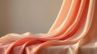 Flowing peach and coral silk fabric with elegant drapes and soft lighting creates luxurious textile background for fashion and interior design projects.