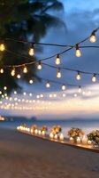 Warm string lights illuminate romantic beachside dinner setup at twilight with candles and flowers creating magical outdoor dining atmosphere for special occasions.