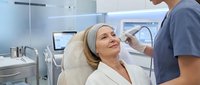 Middle-aged Caucasian woman receiving professional dental treatment from male dentist in modern clinic. Patient relaxation during oral healthcare procedure.