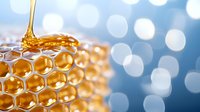 Fresh golden honey dripping onto honeycomb cells with natural bokeh background in blue tones, macro photography showing detailed hexagonal structure and sweet liquid flow.