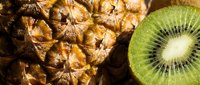 Closeup of fresh pineapple texture beside a halved kiwi fruit, showcasing vibrant tropical colors and natural patterns for food and nutrition concepts.