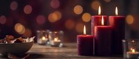 Red candles burning on wooden table with warm bokeh lights creating cozy holiday atmosphere for Christmas celebration and festive home decoration.