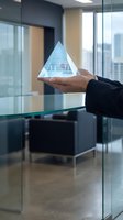 Businessman holding transparent glass pyramid in modern office conference room representing leadership hierarchy and corporate structure concepts.