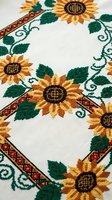Traditional embroidered tablecloth with sunflower motifs and decorative border on white linen fabric showcasing folk art needlework craftsmanship.