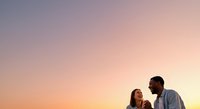 Couple enjoying romantic sunset moment outdoors, man and woman facing each other against golden sky backdrop for relationship and love concepts.
