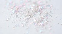 Scattered iridescent glitter particles and sparkles on white surface, suitable for festive backgrounds, cosmetics, and celebration design projects.