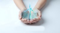 Hands gently holding glowing turquoise butterfly symbolizing transformation, hope and spiritual growth on white background for wellness designs.