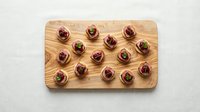 Elegant appetizers with cream cheese and cranberries on wooden cutting board, gourmet finger food presentation for catering and party events.