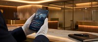 Professional businessman analyzing financial data on smartphone in modern corporate office environment for business technology applications.