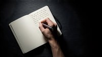 Male hand writing in open notebook on dark surface, capturing journaling, note-taking, and creative writing moments for editorial and lifestyle projects.