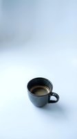 Dark ceramic coffee cup with espresso on clean white background for cafe branding and beverage marketing materials.
