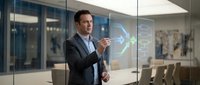 Professional businessman presenting holographic data visualization in modern conference room for corporate technology solutions.